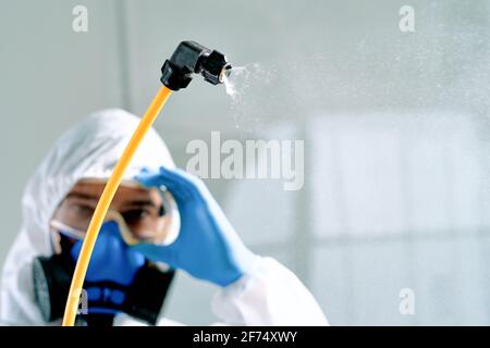 disinfettante professionale in una tuta a rischio biologico che regola gli occhiali di sicurezza. Foto Stock