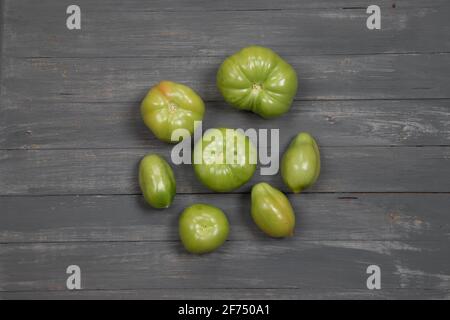 Pomodori verdi non maturi su un tavolo di legno scuro. Foto Stock