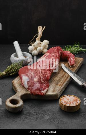 Filetto di manzo crudo a tre punte su tagliere di legno Foto Stock