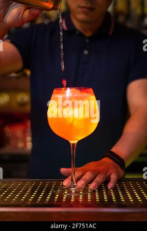 Giovane barista asiatico che versa acqua di soda in pompelmo e gin cocktail al bar Foto Stock