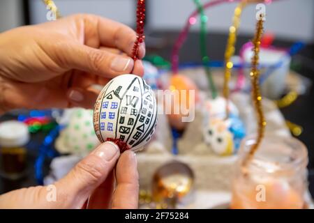 Concetto di attività di pittura e decorazione dell'uovo di Pasqua: Mani umane che tengono uova di Pasqua colorate fatte a mano. Preparazione per le vacanze. Oggetti fissi Foto Stock