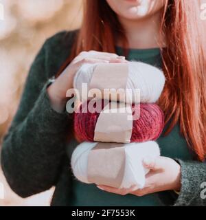 Le mani della persona tengono il filato di alpaca colorato con etichette vuote. Hobby femminile e concetto di maglia per il tempo libero. Foto Stock