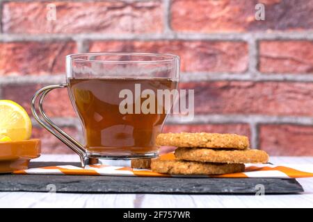 Biscotti di farinata d'avena accompagnati da una tazza di tè e tagliati a fette limone Foto Stock