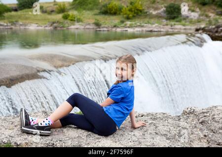 Ritratto di pre teen ragazza che riposa vicino alla cascata del fiume Cijevna. Si chiama Cascate del Niagara montenegrine. Dintorni della città di Podgorica. LUN Foto Stock