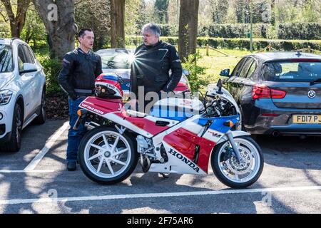 Due uomini adulti che parlano davanti a una Honda parcheggiata motociclo Foto Stock