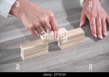 Mano femmina costruzione di un ponte con blocchi di legno; concetto di associazione Foto Stock