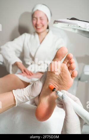 Medico di Podiatrist, esegue la procedura di trattamento delle gambe di una donna. Procedure cosmetiche dei piedi Foto Stock