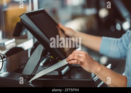 Processo di stampa della fattura per un cliente, processore di carte di credito, stampante per ricevute con bolletta della spesa cartacea e monitor touchscreen, POS Foto Stock