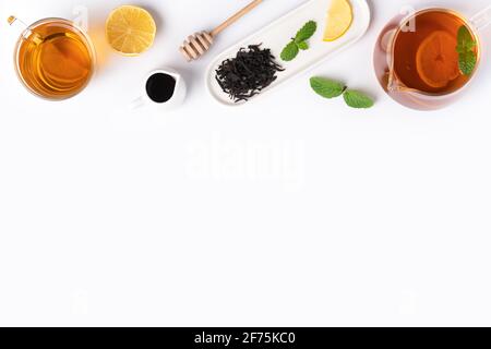 Design concept vista dall'alto del tè nero al miele con limone giallo e foglia di menta su sfondo bianco del tavolo. Foto Stock