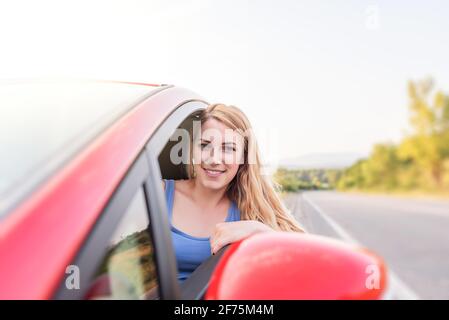 Felice bella donna sta guidando una macchina rossa. Foto Stock