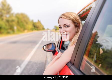 Felice bella donna sta guidando una macchina rossa. Foto Stock