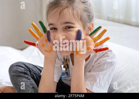 Allegra bambina con palme dipinte con sorrisi. Creatività e arte per bambini Foto Stock