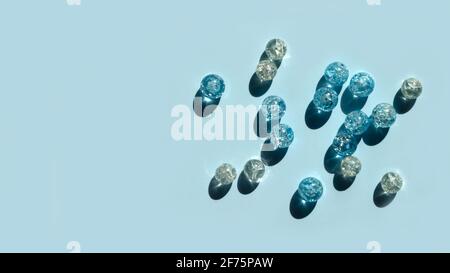 Perline di vetro blu su sfondo blu. Ombre e riflessi duri. Fai da te regalo fatto a mano. Foto Stock