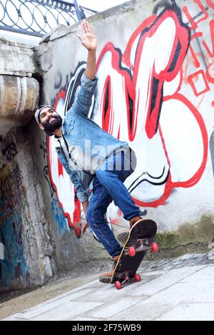 Giovane ragazzo asiatico che salta sul suo skateboard in strada. Foto Stock