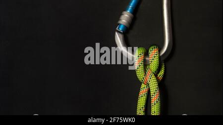 Moschettone verticale con nodo di boatman e corda verde fluorescente uno sfondo nero Foto Stock