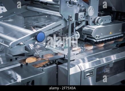 Confezionamento automatico della macchina impacchettatrice a cuscino per prodotti da forno. Macchina confezionatrice per pane, toast, panini e materie plastiche sulla linea di produzione di prodotti da forno Foto Stock