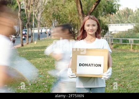 Ritratto di una giovane donna vietnamita abbastanza sorridente in piedi in città parco con dination box Foto Stock