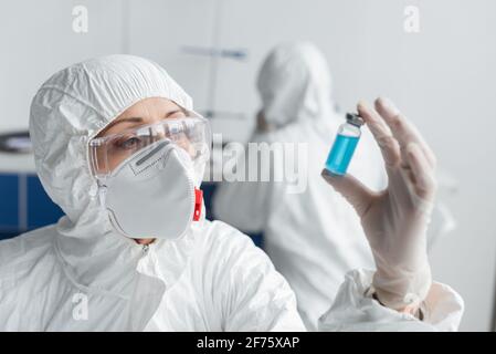 Scienziato che tiene il vaso con il vaccino in primo piano sfocato mentre si lavora in laboratorio Foto Stock