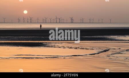 La colorata luce del sole si riflette fuori dal limo sulla spiaggia di Crosby al tramonto nell'aprile 2021. È una delle cento statue di uomini di ferro che compongono Antony Foto Stock