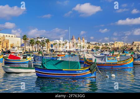 Villaggio di pescatori di Marsaxlokk a Malta, skyline e barche tradizionali maltesi chiamato Luzzu Foto Stock