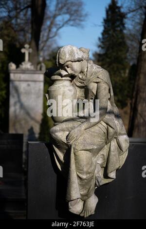 Antica scultura in pietra di una donna con urna su una lapide nel cimitero evangelico di Augusta a Varsavia, Polonia Foto Stock