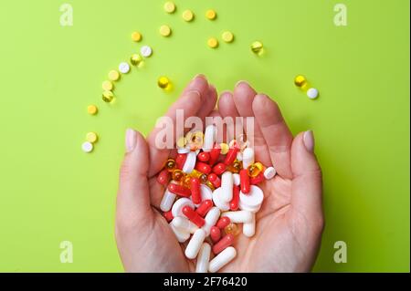 Vista ritagliata delle mani della donna che tengono un sacco di pillole o vitamine su sfondo verde pastello. Foto di alta qualità Foto Stock