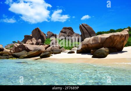 Spiaggia di Anse Marron con grandi massi di granito sull'isola di la Digue, Seychelles. Paesaggio tropicale con cielo soleggiato. Destinazione di viaggio di lusso. Foto Stock