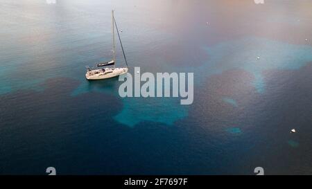 Vista aerea del drone di una barca a vela ancorata in una baia dell'isola di Cabrera nell'arcipelago delle Isole Baleari, Spagna Foto Stock