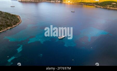 Vista aerea del drone di una barca a vela ancorata in una baia dell'isola di Cabrera nell'arcipelago delle Isole Baleari, Spagna Foto Stock