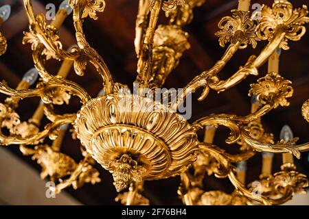 Primo piano di un lampadario dorato. Lampadario con candelieri e motivi. Foto Stock