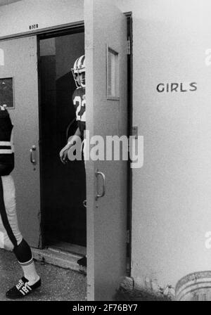 I giocatori di calcio delle scuole superiori escono da uno spogliatoio per ragazze prima di giocare a una partita di calcio nel sud della Florida. Circa anni '60... Foto Stock