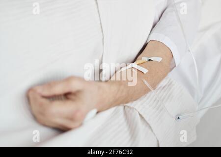 Primo piano dei tubi di gocciolamento ev e del catetere in mano a un uomo anziano irriconoscibile, spazio di copia Foto Stock