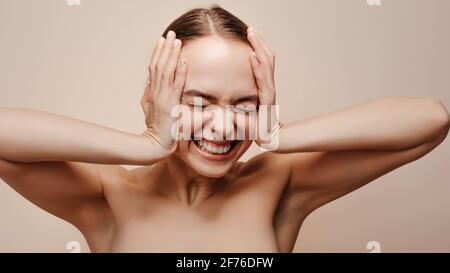 Ritratto emozionale di giovane donna che ha premuto le mani a. la testa Foto Stock