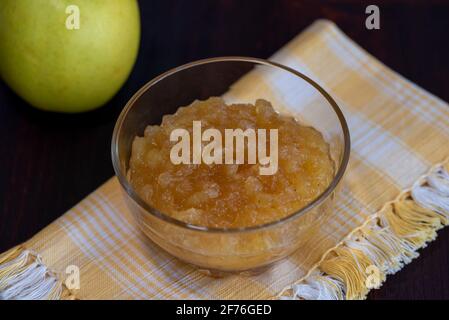 salsa di mele in un bicchiere di vetro su una superficie di legno Foto Stock
