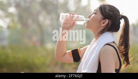 Bella atleta di fitness donna che beve acqua dopo l'allenamento all'alba mattina in estate nel parco Foto Stock