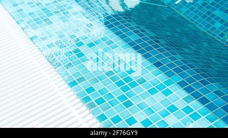 Piscina vista dall'alto da vicino. Piscina acqua superficie sfondo con spazio di copia. Tessitura di tessere quadrate di mosaico blu in un centro benessere termale. Scarico gr Foto Stock