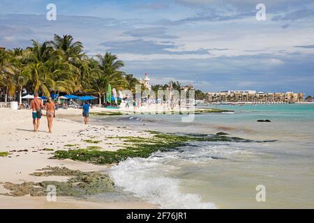 Turisti occidentali che camminano sulla spiaggia di sabbia bianca e alberghi lungo Playa del Carmen, Riviera Maya, Solidaridad, Quintana Roo, Penisola di Yucatán, Messico Foto Stock