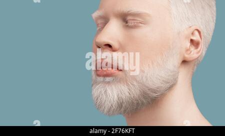 Uomo albino calmo bearded con occhi chiusi poggiati su sfondo turchese, panorama con spazio vuoto Foto Stock