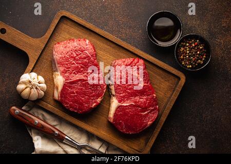 Due bistecche di carne cruda su tavola di legno Foto Stock