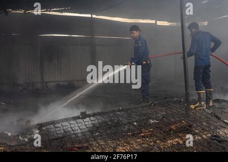 I vigili del fuoco vedevano spegnere alcuni degli articoli ancora in fiamme nel warehouse.Today un incendio scoppiò e ingolfò un magazzino a Kendari. Secondo i testimoni oculari, l'incendio è stato innescato da un corto circuito di elettricità che ha catturato fiamme dopo aver colpito una bombola di gas e una motocicletta all'interno del magazzino. Foto Stock