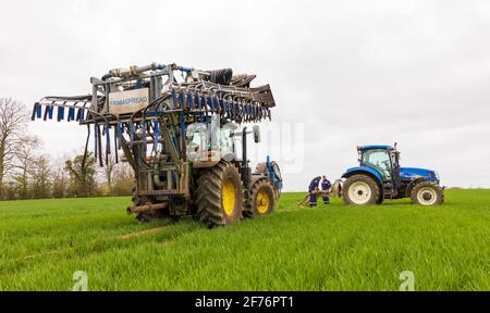 Uomini che preparano il trattore con una barra dribble dello spandipaglia Tramspread ripiegata. Hertfordshire, Regno Unito Foto Stock