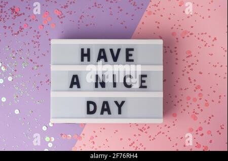 Buona giornata - testo sul display lightbox on sfondo viola e rosa con paillettes Foto Stock