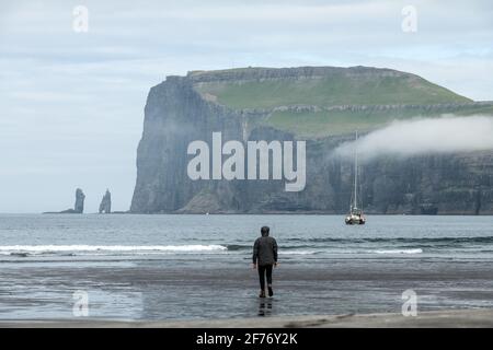 Turista solitario sulla spiaggia di Tjornuvik sull'isola di Streymoy, Isole Faroe, Danimarca. Fotografia di paesaggio Foto Stock