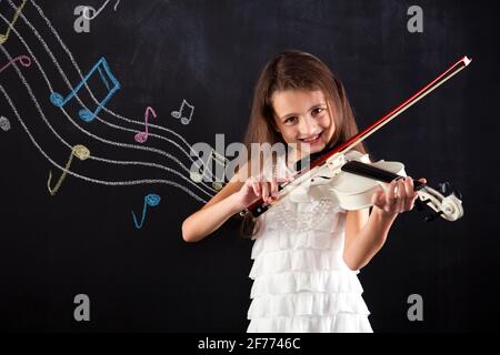 La bambina che suona il violino accanto a una lavagna Foto Stock