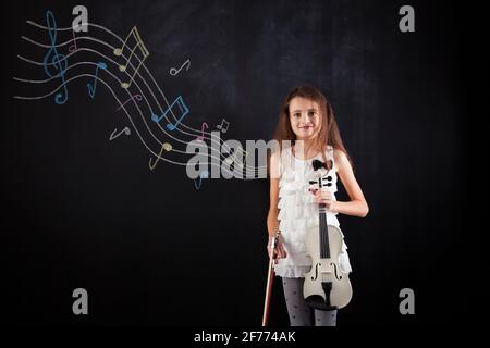 La bambina che suona il violino accanto a una lavagna Foto Stock