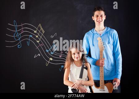 Fratello e sorella che suonano uno strumento musicale accanto a a. lavagna Foto Stock