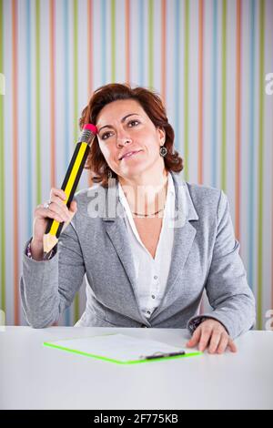 Donna d'affari che scrive con una matita gigante al suo ufficio Foto Stock