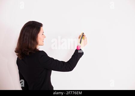 Donna d'affari che scrive sulla parete con una matita grande Foto Stock