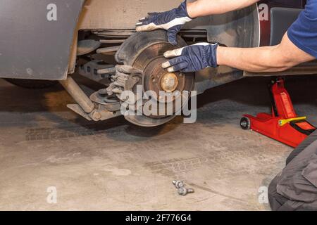 Primo piano su come un uomo controlla i dischi dei freni su un'auto. Concetto di trasporto. Svezia. Foto Stock