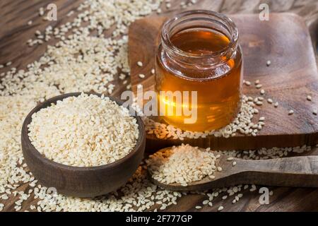 Olio di sesamo in vaso di vetro e semi di sesamo su legno Cucchiaio - Sesamum indicum Foto Stock